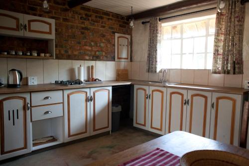 een keuken met witte kasten en een raam bij Stone Cottage in Tierpoort