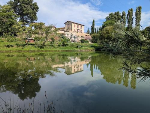 a house is reflected in the water of a lake at Maison de campagne 8 couchages avec piscine et lacs in Sainte-Radegonde