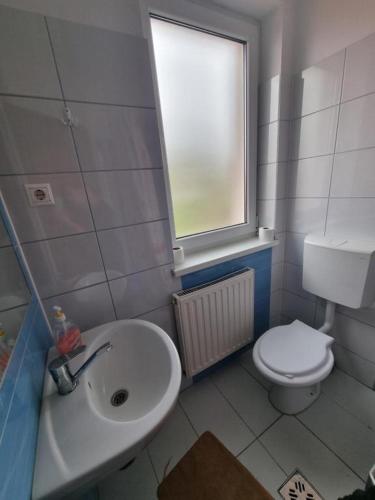 a bathroom with a sink and a toilet and a window at Kincses Panzió in Praid
