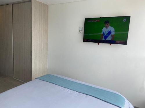 a bedroom with a bed with a tv on the wall at Usaquén Vida & Cultura suite in Bogotá