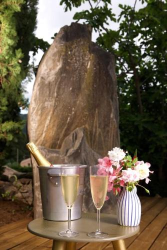 a table with two glasses of champagne and a vase of flowers at La Villa Du Menhir Chambre d'hôtes in Bize-Minervois