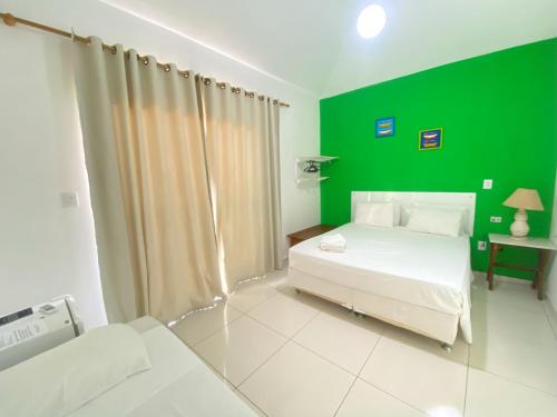 a green bedroom with a white bed and a green wall at Pousada Maravilha de Paraty in Paraty