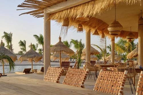 a restaurant with chairs and umbrellas on the beach at OKAÏ Oasis Desert Senegal in Lompoul