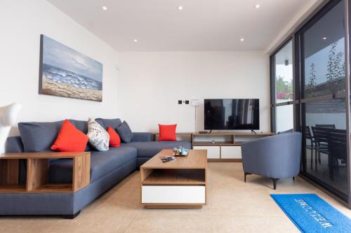 a living room with a blue couch and a tv at Tills Beach Resort in Fetta