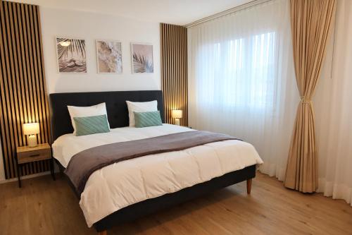 a bedroom with a bed with two lamps and a window at Top duplex Apartment Zurich-Limmattal in Killwangen