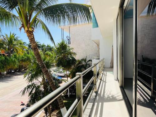a balcony with a palm tree and a building at Experience tranquility and comfort accommodation, near main attractions in Riviera Maya in Lafitte