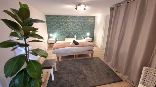 une chambre avec un lit et une plante en pot dans l'établissement La Petite Cuvée confort & elegance, à Beaune