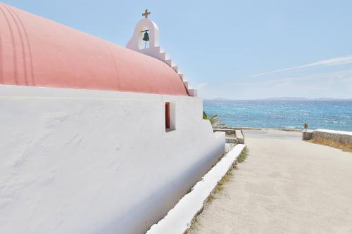 a white building with a red roof next to the ocean at Baba Houlakia in Houlakia