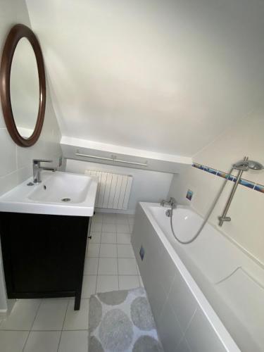 une salle de bain avec un lavabo, une baignoire et un miroir dans l'établissement Maison de Bourg, à Hermanville-sur-Mer