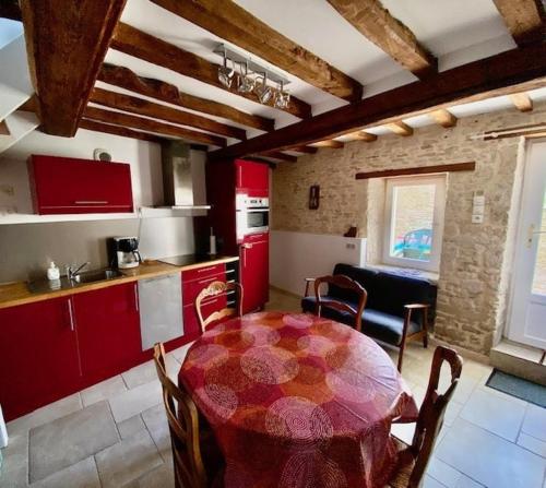 une cuisine avec une table et une cuisine avec des placards rouges dans l'établissement Maison de Bourg, à Hermanville-sur-Mer