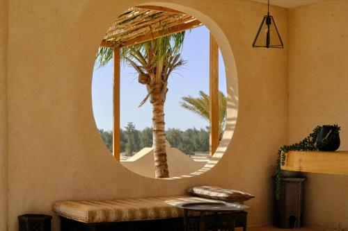 a circular mirror in a room with a palm tree at OKAÏ Oasis Desert Senegal in Lompoul