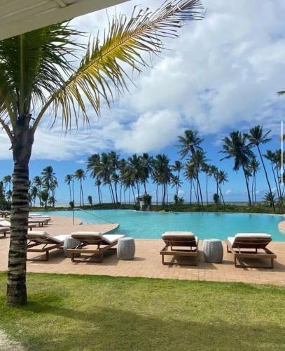 a pool with picnic tables and a palm tree at casa condomínio praia do castelo in Mata de Sao Joao