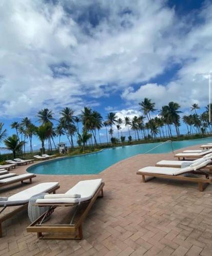 a pool with chaise lounge chairs and palm trees at casa condomínio praia do castelo in Mata de Sao Joao