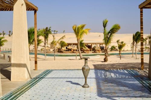 a vase in the middle of a courtyard with palm trees at OKAÏ Oasis Desert Senegal in Lompoul