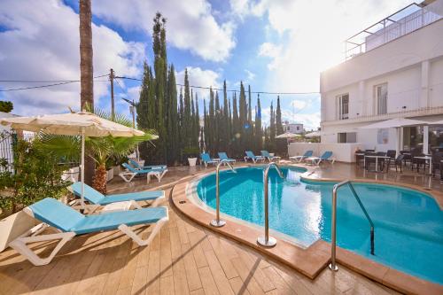 a pool at a hotel with chairs and an umbrella at INNER Hotel Rupit "Adults Only" in Cala d´Or