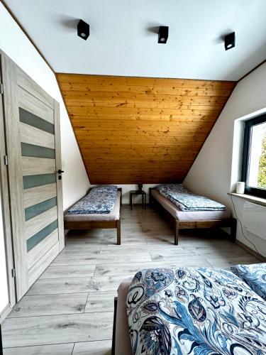 a room with two beds and a wooden ceiling at Domek wypoczynkowy z sauną i jacuzzi "ELDORADO" in Lubawka