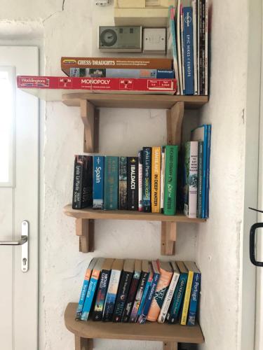 a bunch of books are sitting on a shelf at Dolphin Cottage - Child & Pet Friendly in Ballintoy