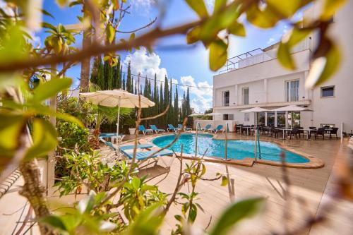 a swimming pool with chairs and umbrellas next to a building at INNER Hotel Rupit "Adults Only" in Cala d´Or