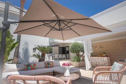 a patio with a couch and a large umbrella at Nilu al Mare - Villa pool & sea Monopoli in Monopoli