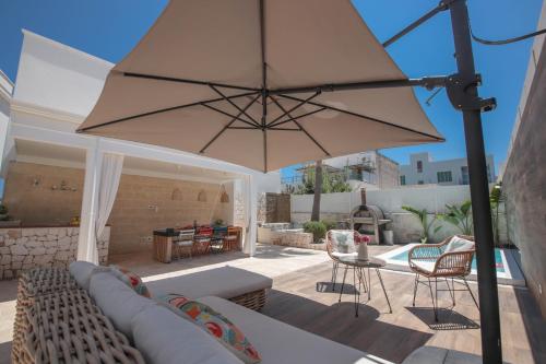 a living room with a couch and a large umbrella at Nilu al Mare - Villa pool & sea Monopoli in Monopoli