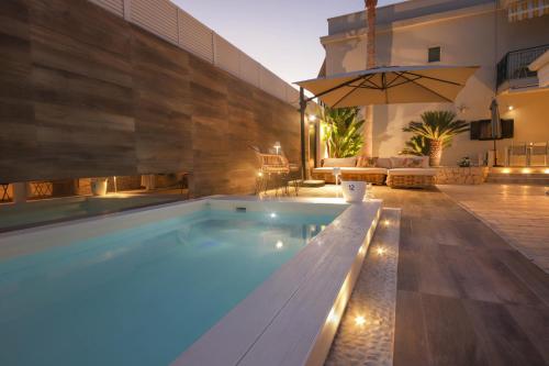 a swimming pool with a bench and an umbrella at Nilu al Mare - Villa pool & sea Monopoli in Monopoli