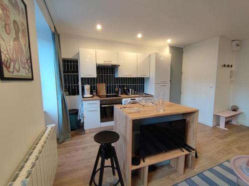 Una cocina con gabinetes blancos y una barra con un taburete. en Marine 2, en Cherbourg-en-Cotentin