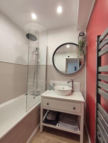 une salle de bain avec un lavabo, une baignoire et un miroir dans l'établissement Marine 2, à Cherbourg en Cotentin