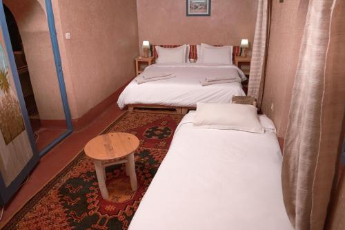 a small room with two beds and a table at Dar Mouna in Aït Ben Haddou