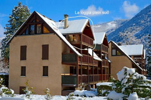 un grand bâtiment avec de la neige sur le toit dans l'établissement Agréable T2, 700m du pôle thermoludique de Luchon, à Luchon