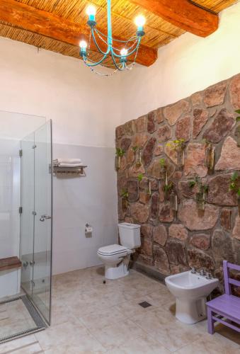 a bathroom with two toilets and a stone wall at Ecohotel Posta de Purmamarca in Purmamarca