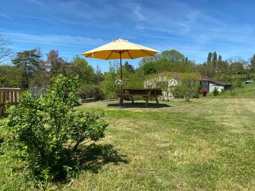 a picnic table with an umbrella in a yard at Aux Trois Mûriers in Villeneuve-sur-Lot
