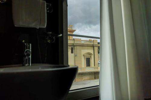 a bathroom with a view of a building from a window at Hotel Exclusive in Agrigento