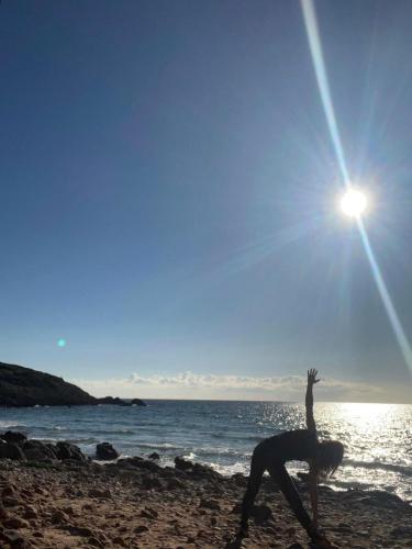 a woman doing a yoga pose on the beach at Agriturismo Glamping Erbe Matte in SantʼAntìoco