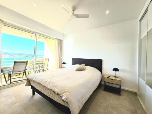 une chambre blanche avec un lit et une grande fenêtre dans l'établissement Venise1, 4 pers, front de mer, vue étang, clim, à Fréjus