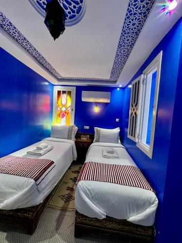 two beds in a room with blue walls at RIAD CHENGLI 蓝城里 in Chefchaouene