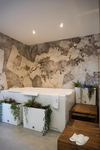 a bathroom with a bath tub and plants on a wall at Etna Exclusive in Ragalna