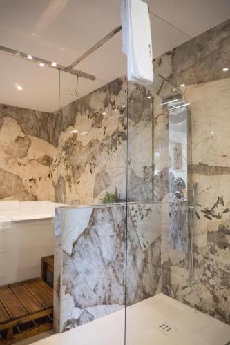 a shower in a bathroom with a stone wall at Etna Exclusive in Ragalna