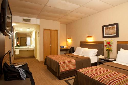 a hotel room with two beds and a television at Land Express Neuquén in Neuquén