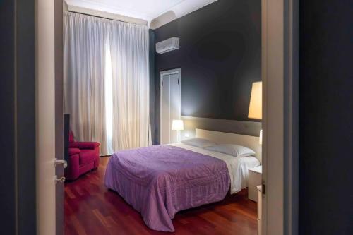 a bedroom with a bed and a red chair at Hotel Exclusive in Agrigento