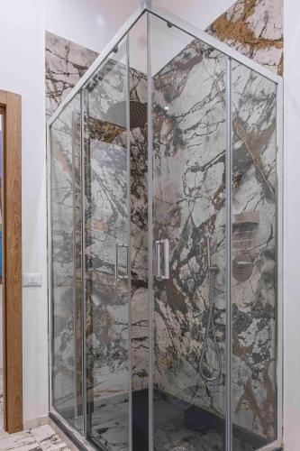 a glass shower in a room with a stone wall at Hotel Exclusive in Agrigento