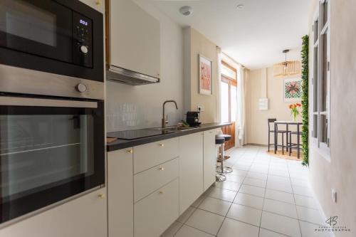 La cuisine est équipée de placards blancs et d'un four micro-ondes noir. dans l'établissement Le Loft du Midi - Full Centre, à Saint-Gaudens