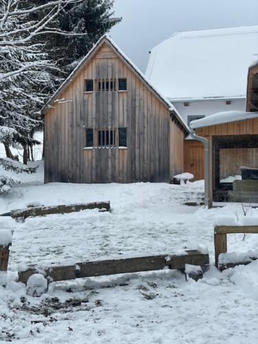 a wooden barn with snow on the ground at Pilnikárna in České Křižánky