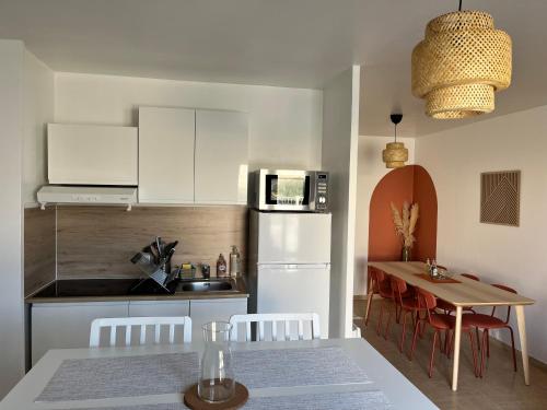 a kitchen and dining room with a table and a refrigerator at Maison familiale et chaleureuse à la chaume av 2 chambres, terrasse, wifi in Les Sables-dʼOlonne
