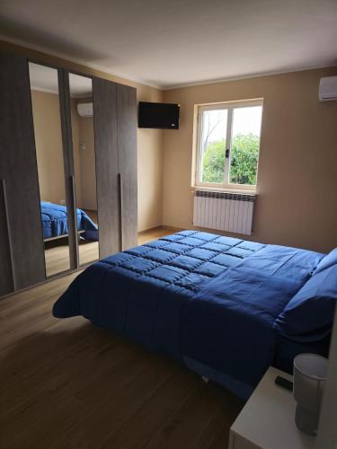 a bedroom with a blue bed and a large window at Maxi Center in Vairano Scalo