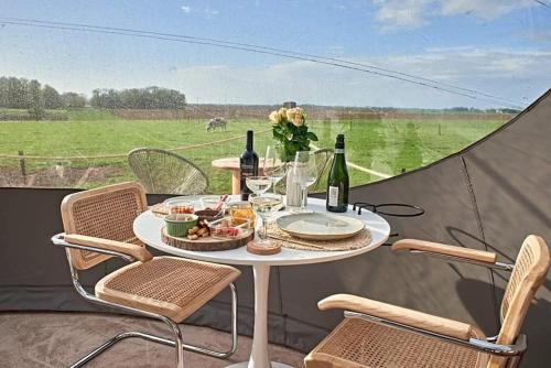 a table with two chairs and a table with wine bottles at La Bulle Céleste in Faimes