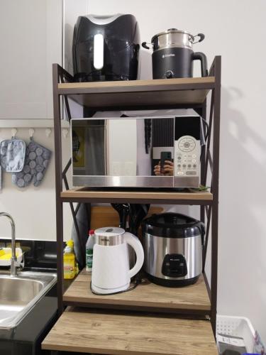 a kitchen shelf with a microwave and other appliances at E214 Place at SMDC Cheer Residences in Marilao