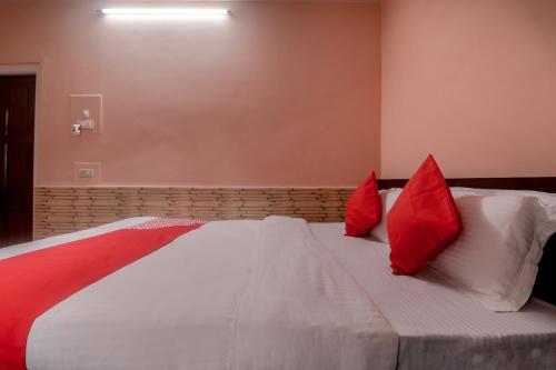 a bedroom with a bed with red pillows on it at Collection O Trinayan Associates in Dibrugarh