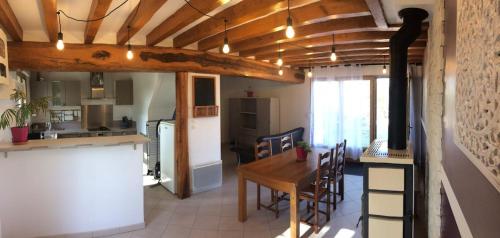 a kitchen and dining room with a wooden table and chairs at Moulin de la Ville Chamblon en Pleine nature parmi les chevaux proche château thierry in Montfaucon