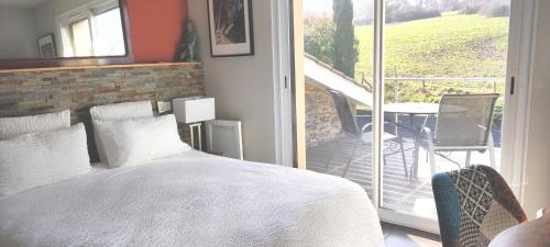 a bedroom with a bed and a balcony with a table at Les Bruyères in Civrieux-dʼAzergues