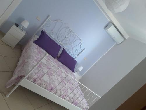 un piccolo letto con lenzuola e cuscini viola e bianchi di Iriss a Taormina